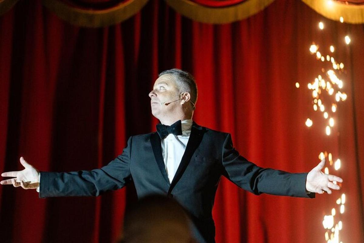 a man in a tuxedo standing in front of a red curtain