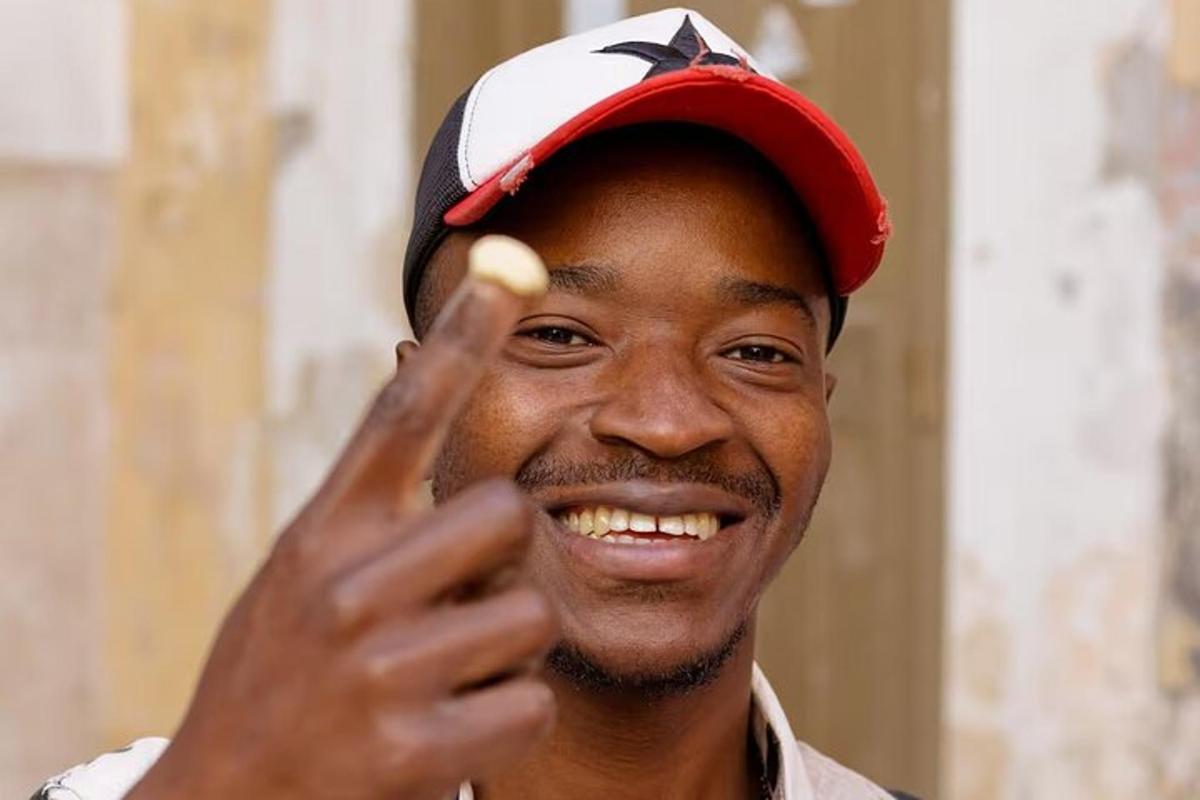 a man wearing a baseball cap with his hand up