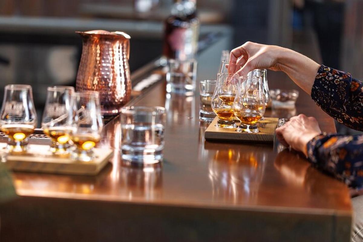 a woman sitting at a bar with glasses of whiskey