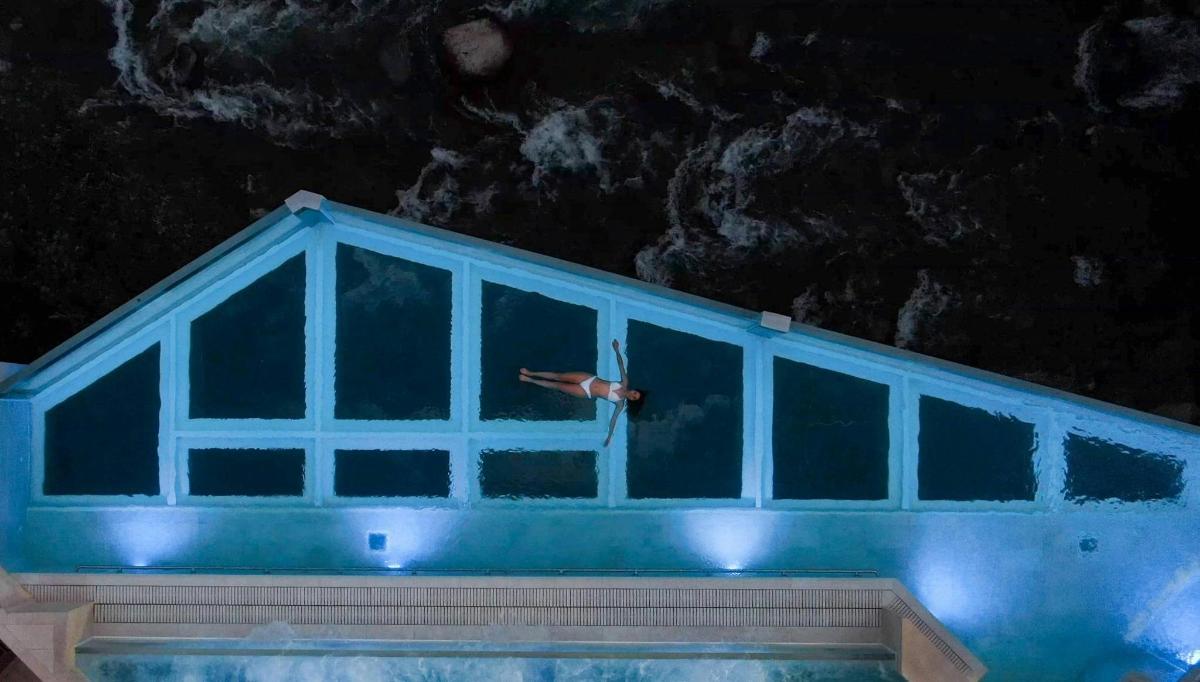a person swimming in a pool at night