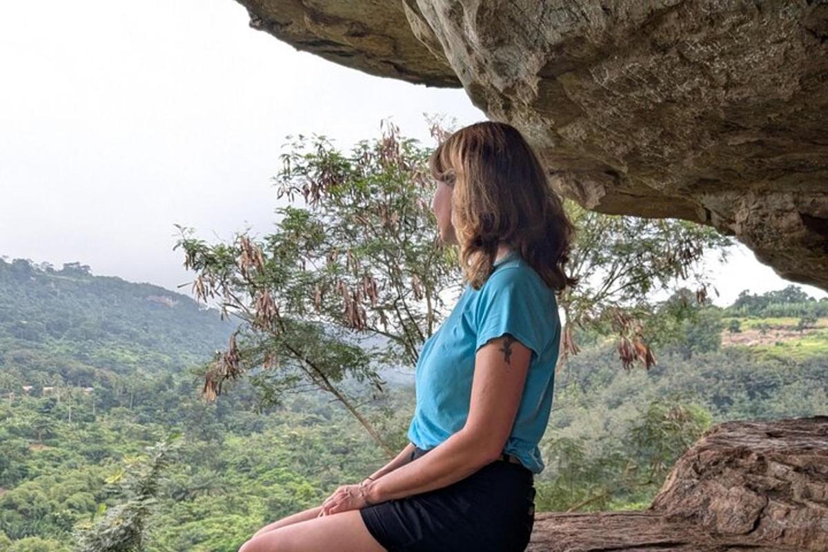 a woman sitting on a rock looking out at the mountains