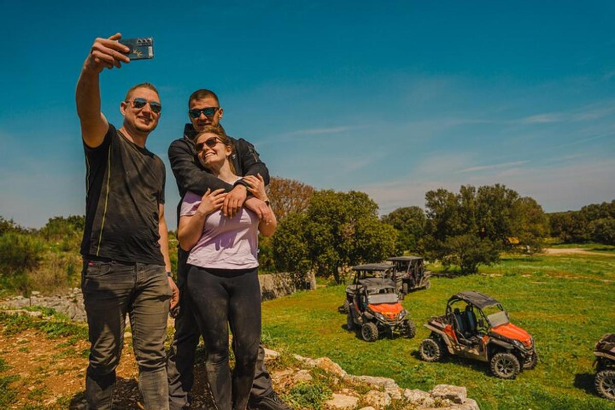 skupina tří lidí stojících na poli s fotoaparátem