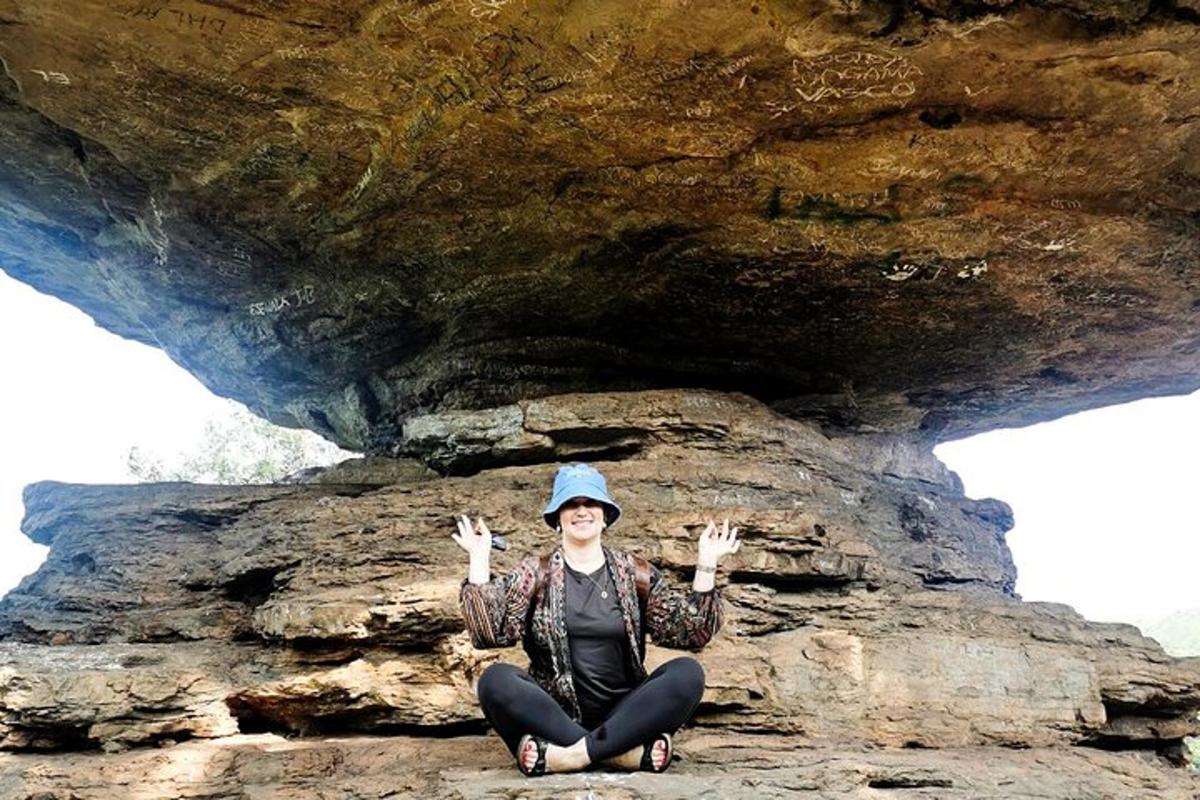 a woman sitting on a rock with her hands in the air