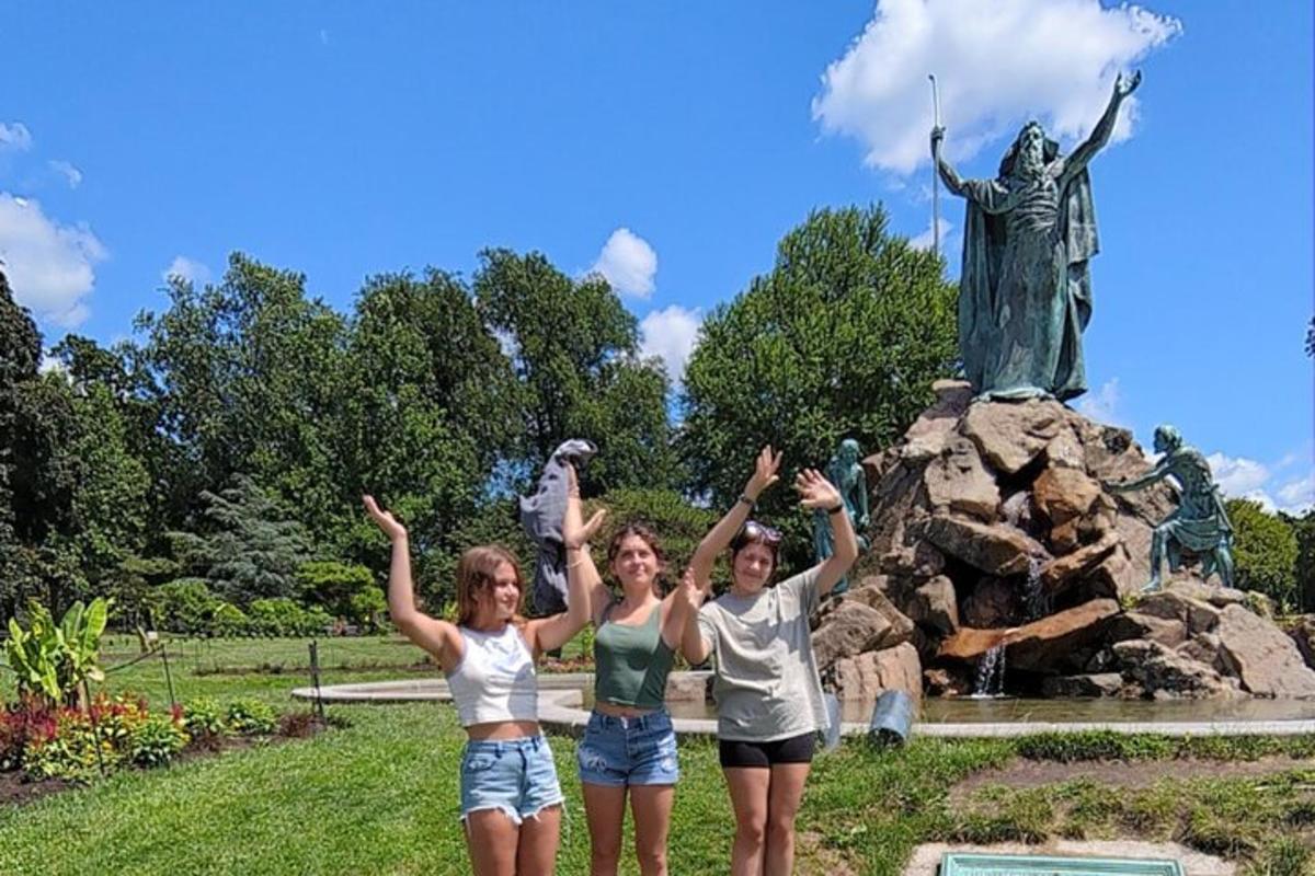three girls are standing in front of a statue