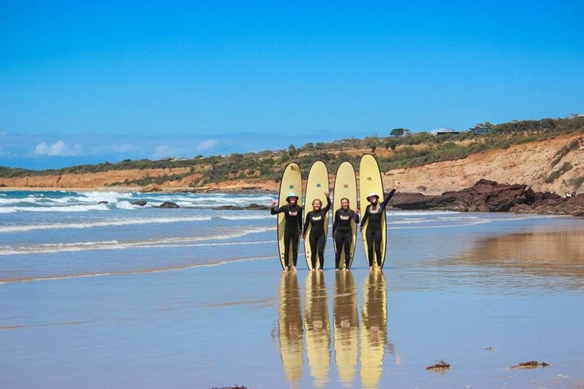 three people standing on the beach with their surfboards
