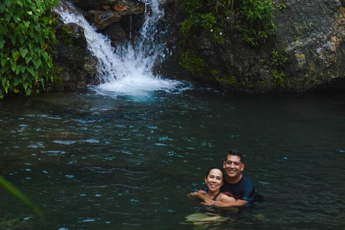 Un hombre y una mujer nadando en una cascada