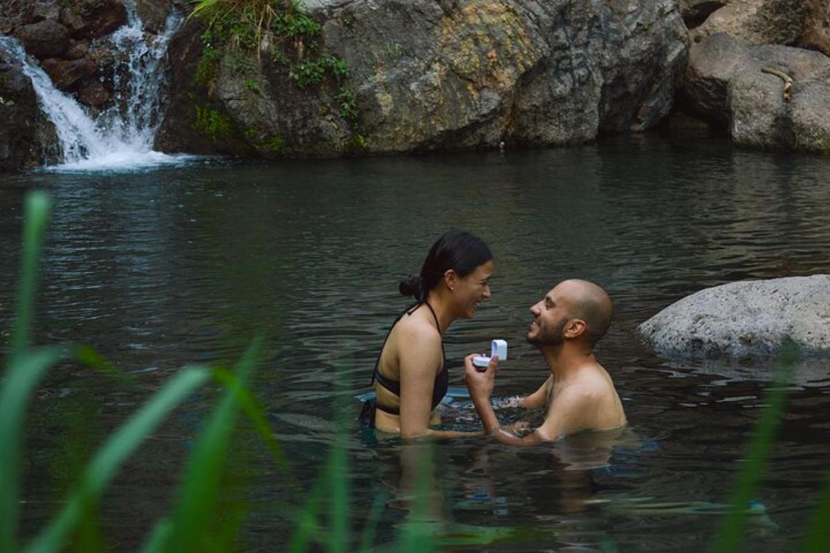 Un hombre y una mujer en el agua cerca de una cascada