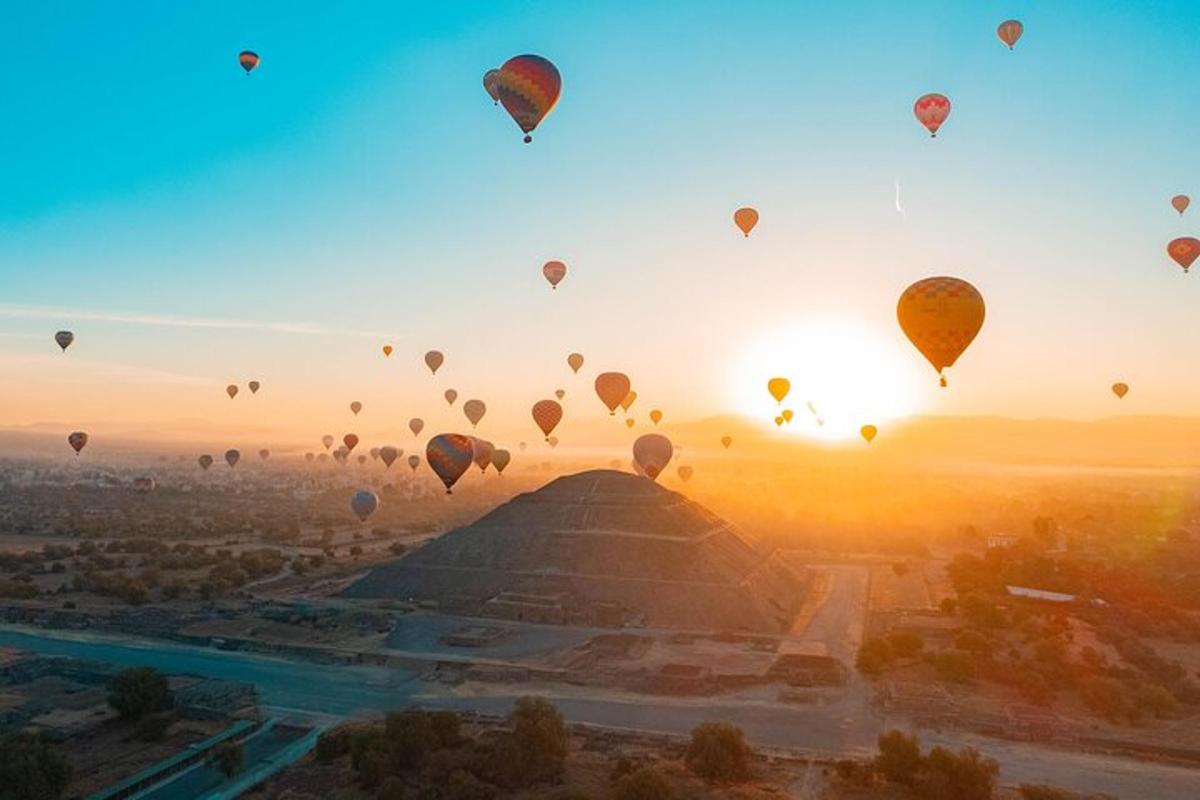 a group of hot air balloons flying over the pyramids