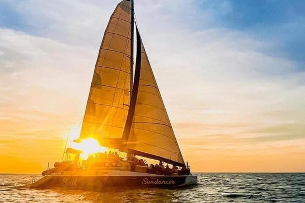 a sailboat in the ocean with the sun setting
