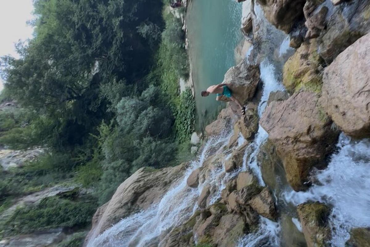 a man on a rock wall next to a waterfall