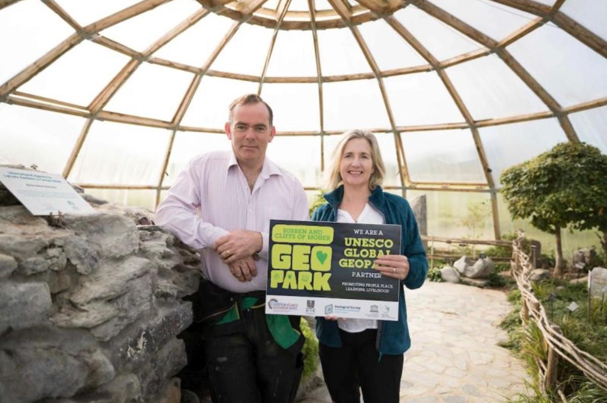 muž a žena držící ceduli ve skleníku