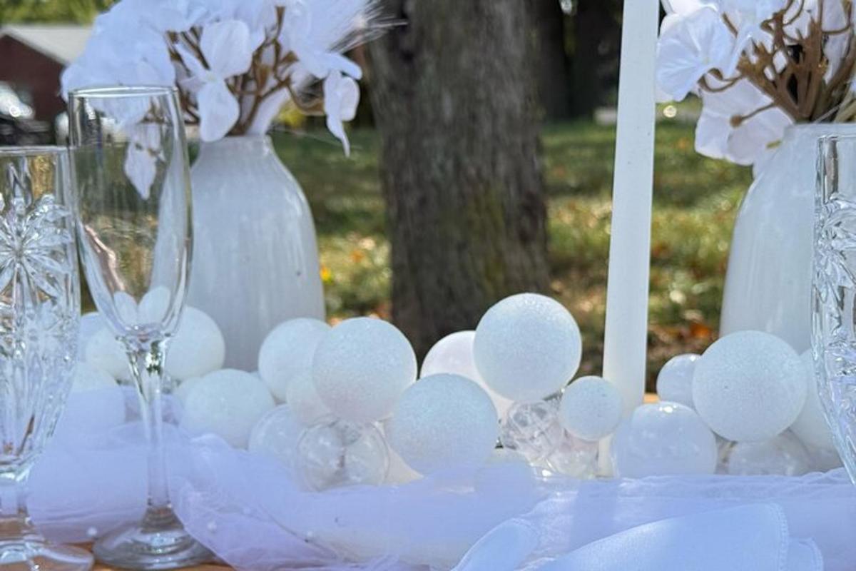 a table with wine glasses and white vases and flowers