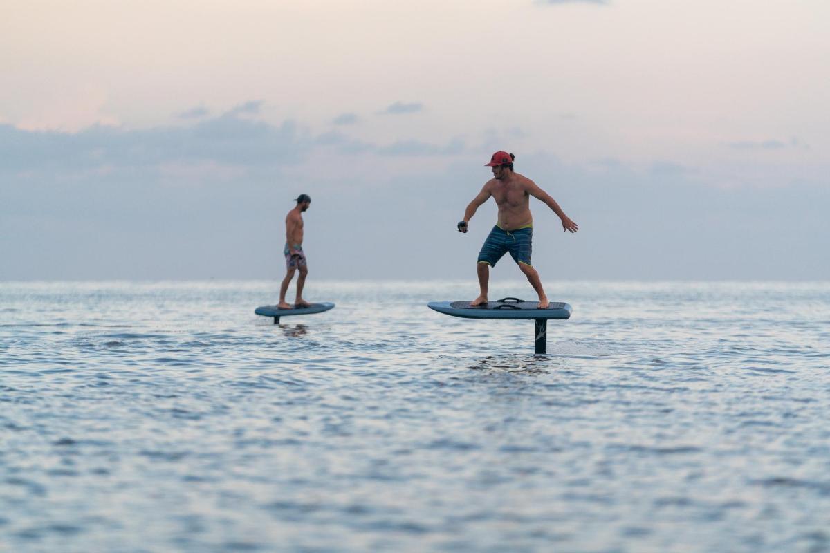 두 남자가 물 속 서핑보드 위에 서 있다