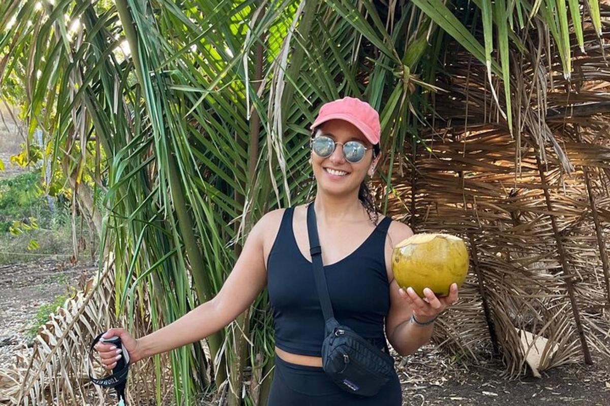 a woman holding a coconut in front of a palm tree