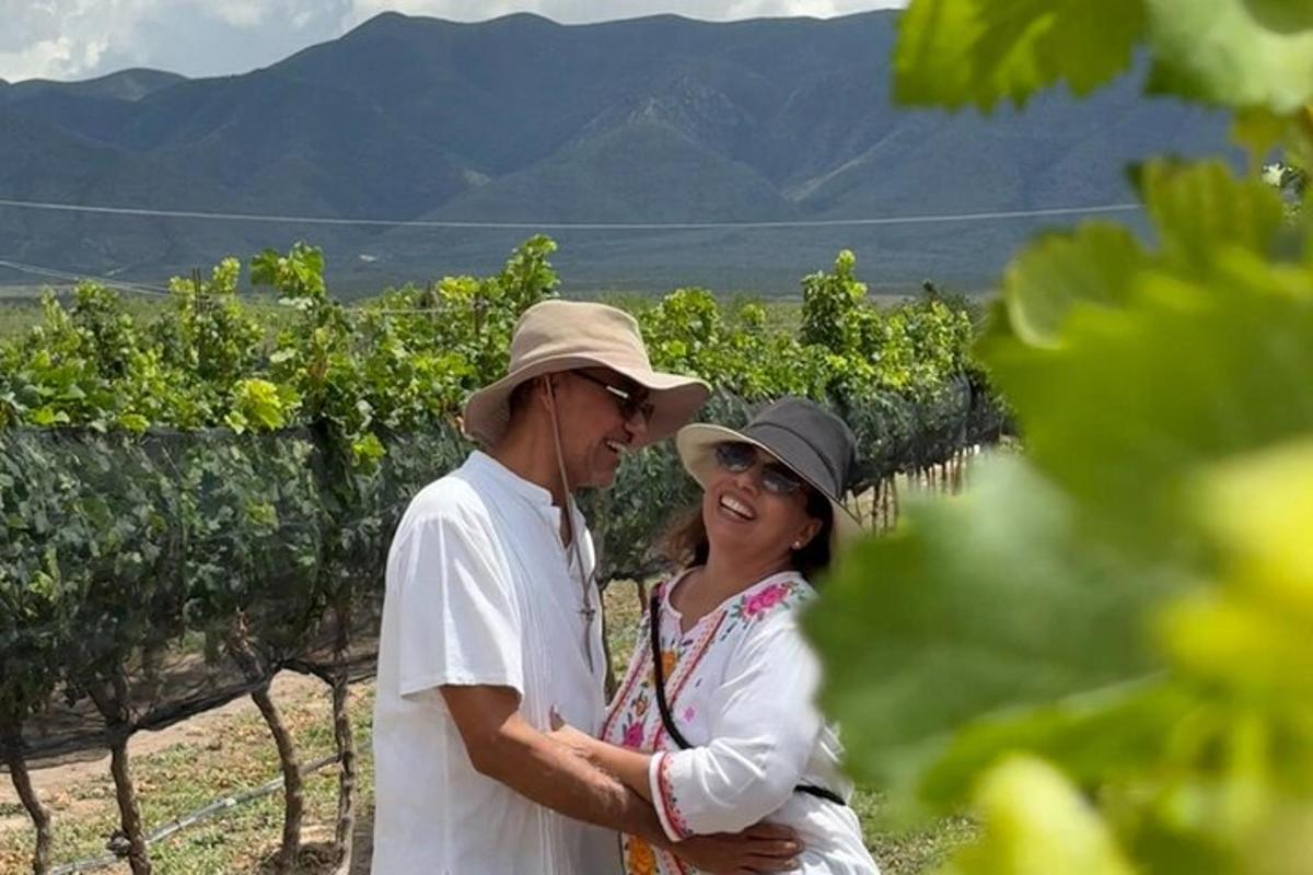 a man and woman standing in front of a vineyard