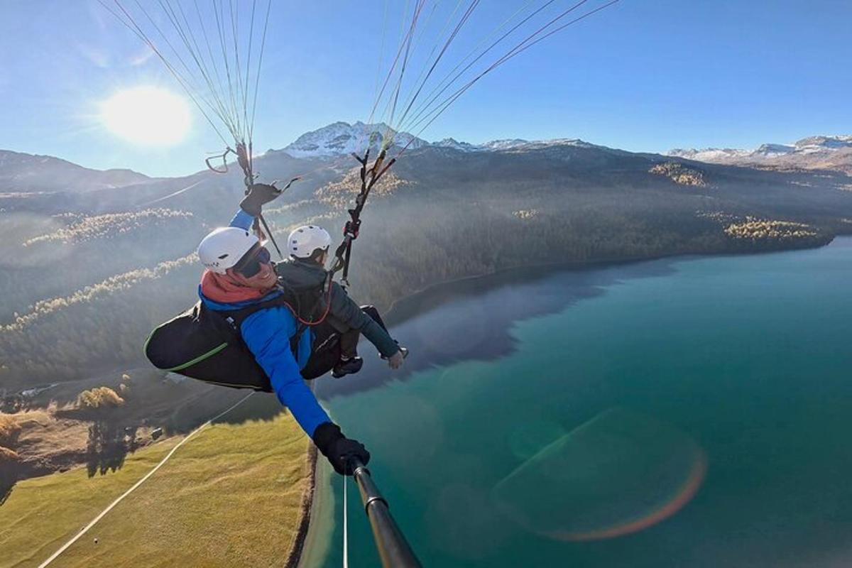 two people are riding a parachute over a lake
