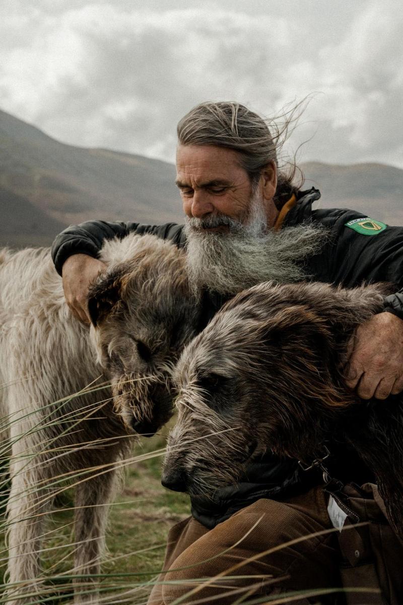 a man with a long beard standing next to a cow