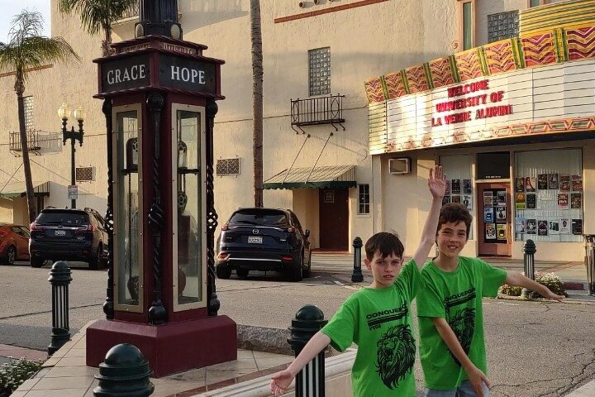 two boys in green shirts standing next to a street