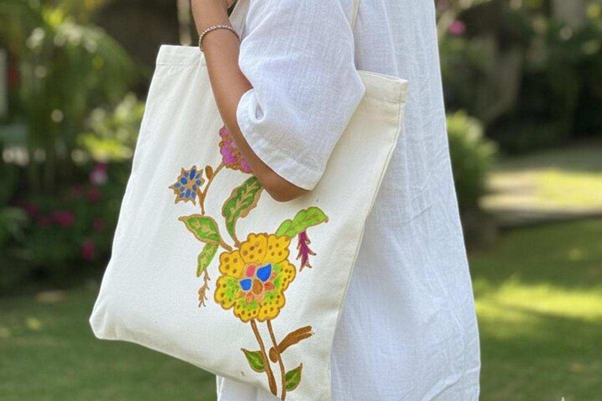 a woman holding a white tote bag with a flower on it