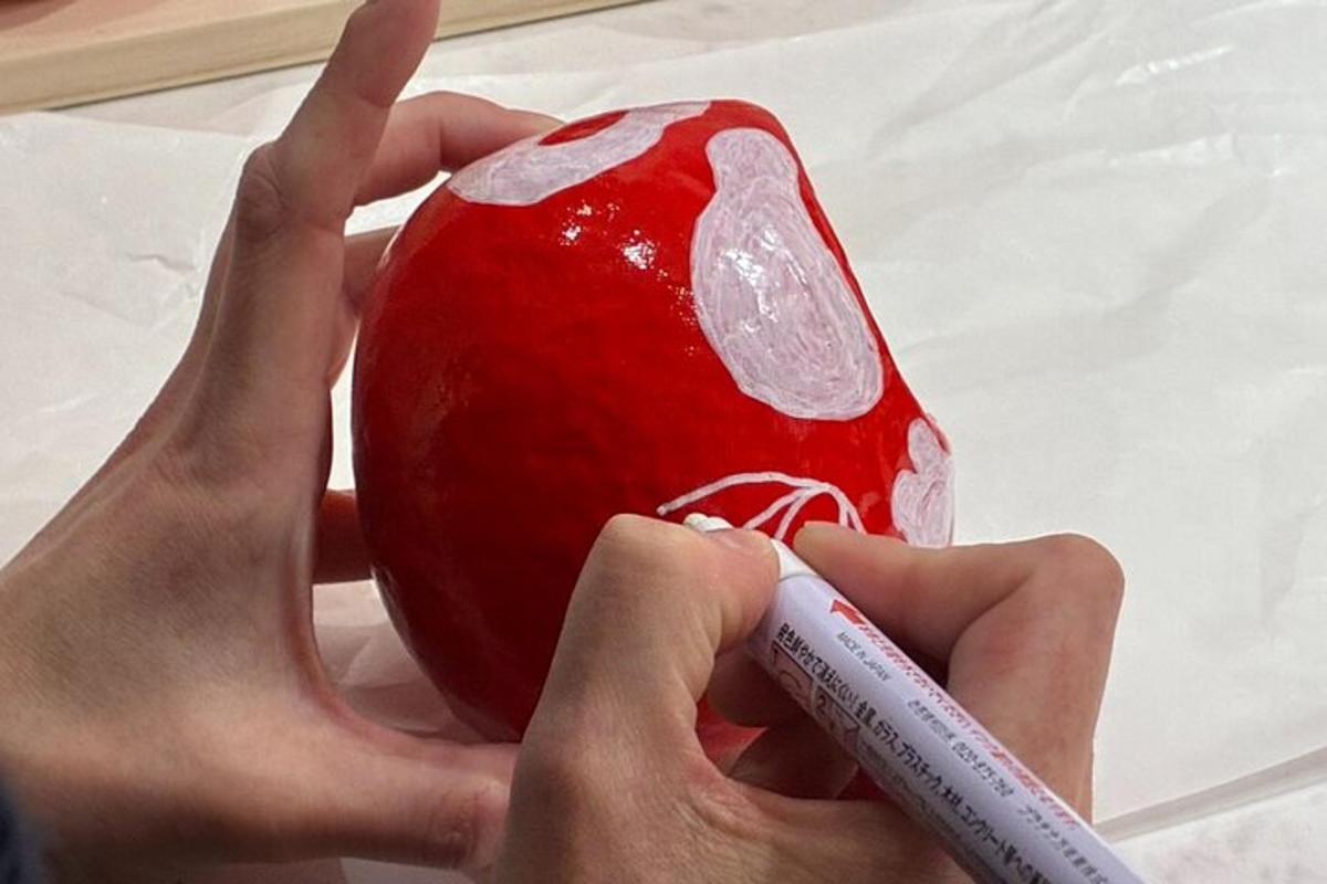 člověk maluje červené jablko fixem