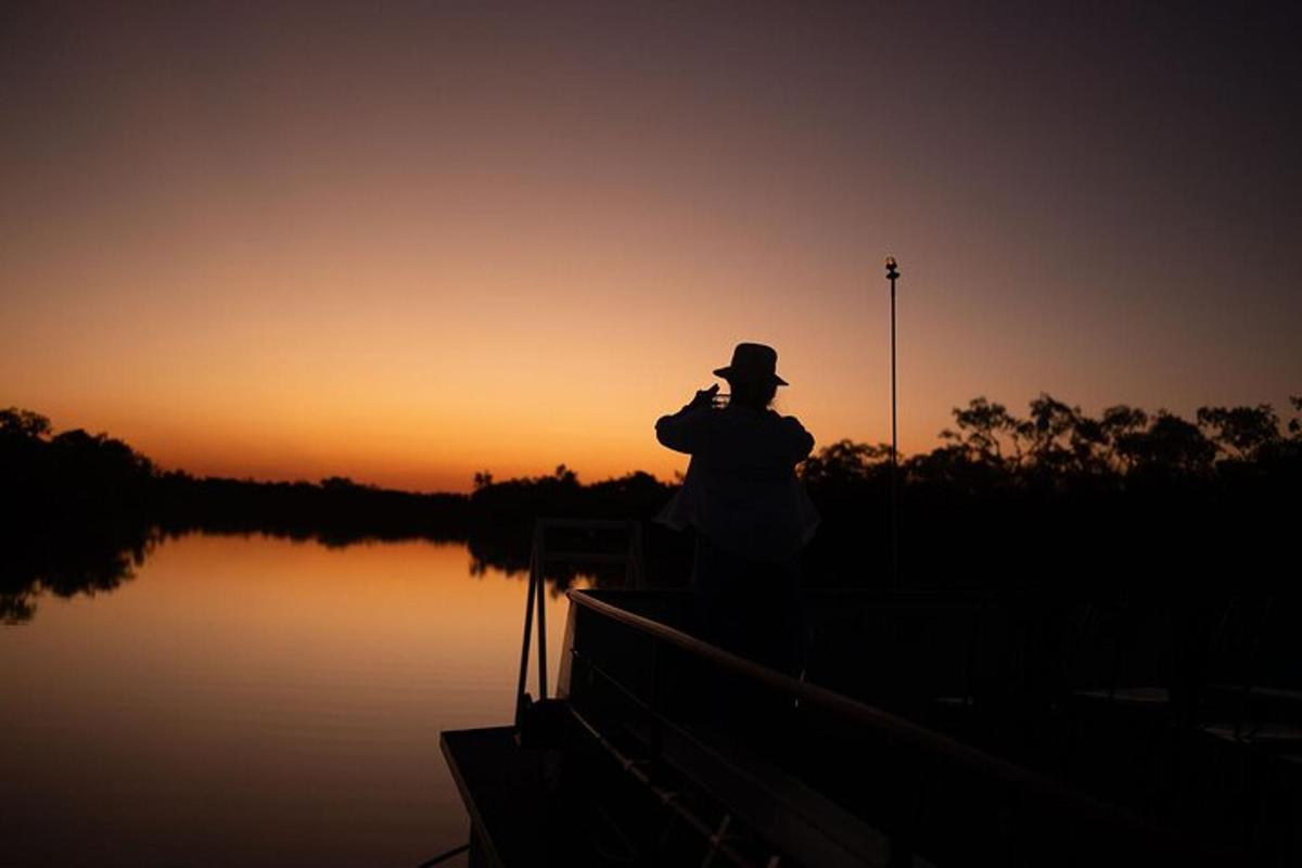 一名男子站在码头上拍摄日落。