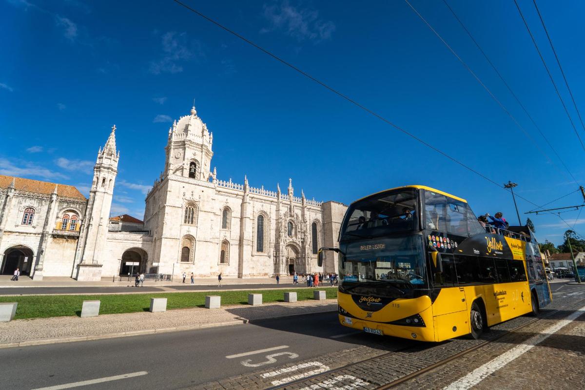 a yellow double decker bus driving past a building