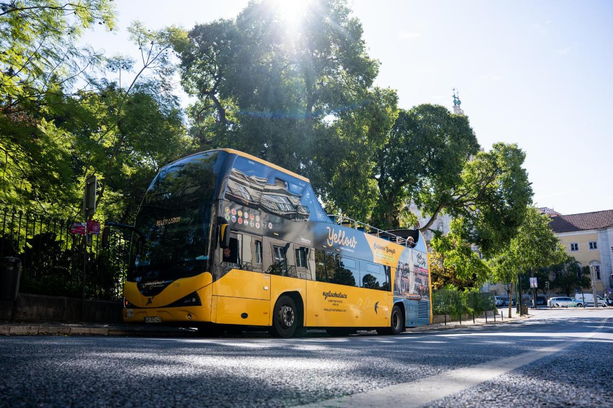 a yellow double decker bus driving down a street