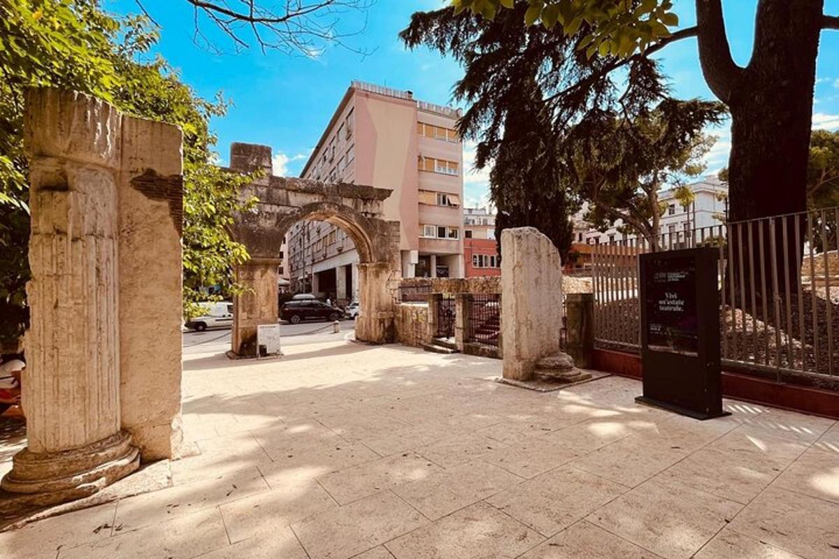 an arch in a city with a fence and trees