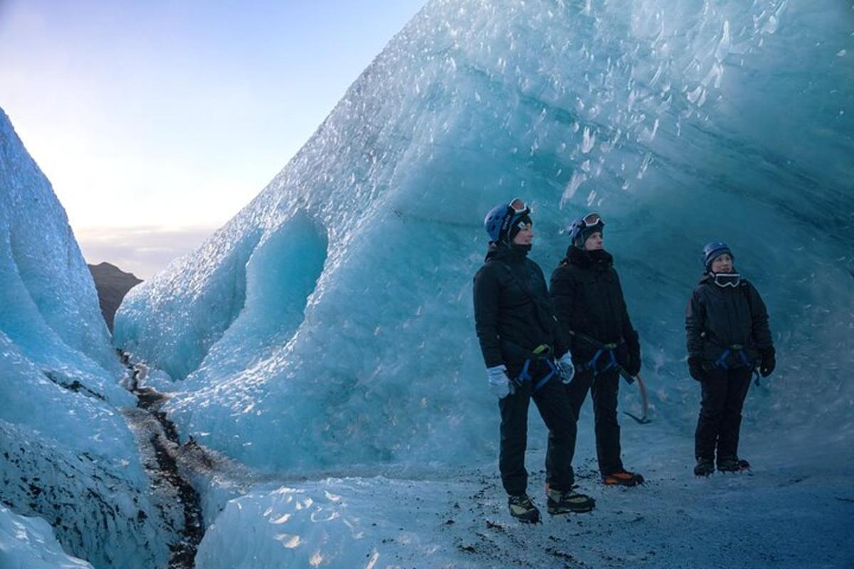 three people standing in front of an ice cave