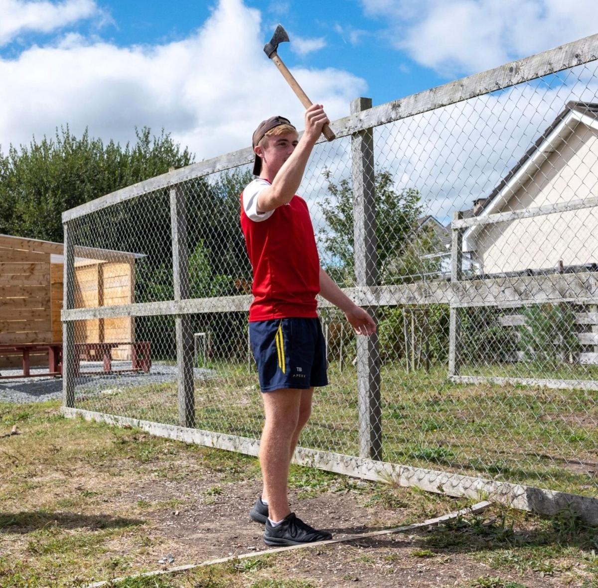 a woman holding a baseball bat in front of a fence
