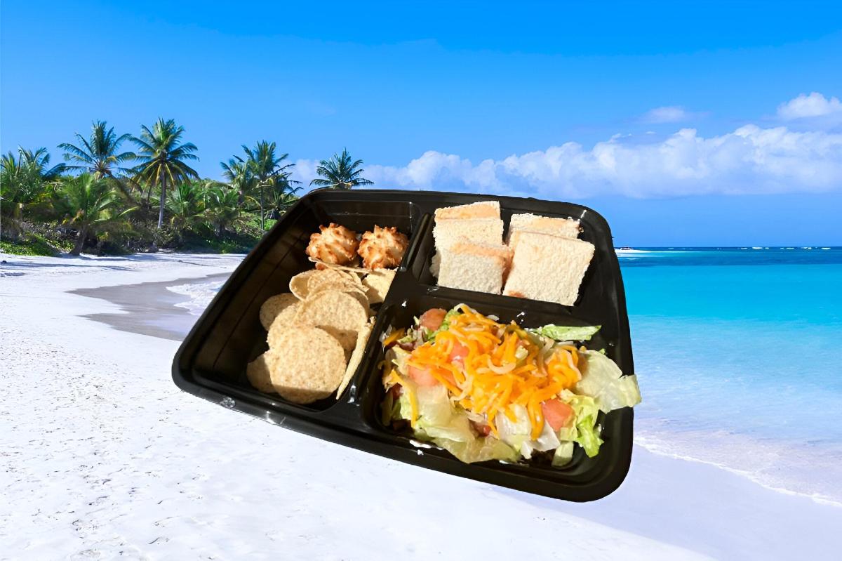 a black tray of food on a beach