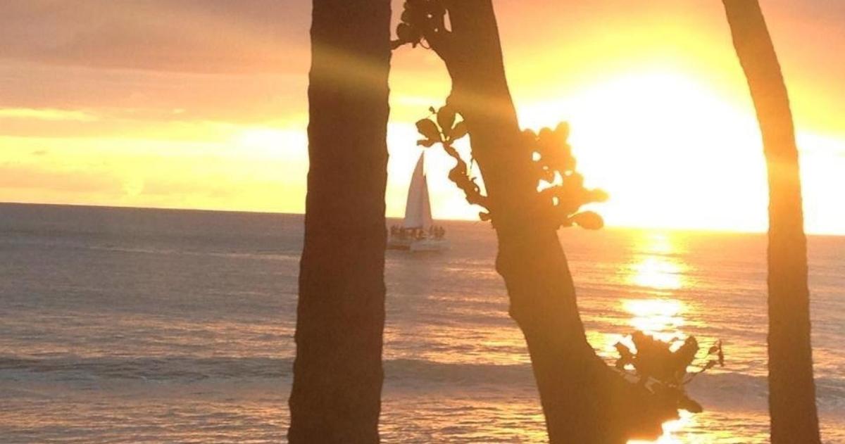 a sail boat in the ocean with a lighthouse in the distance