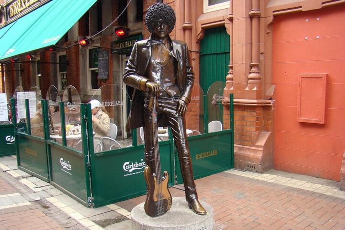 a statue of a boy with a guitar on a street