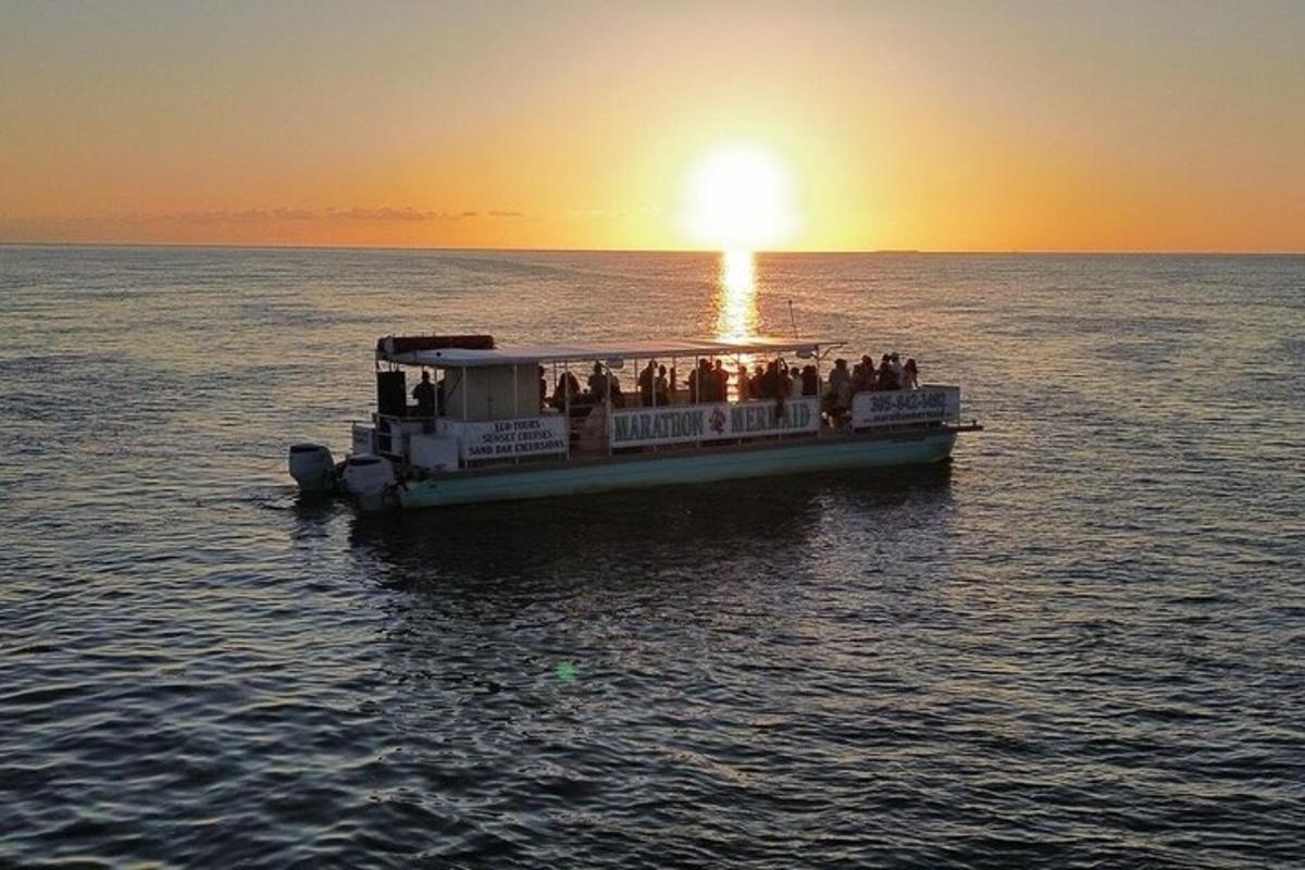 a group of people on a boat in the water at sunset