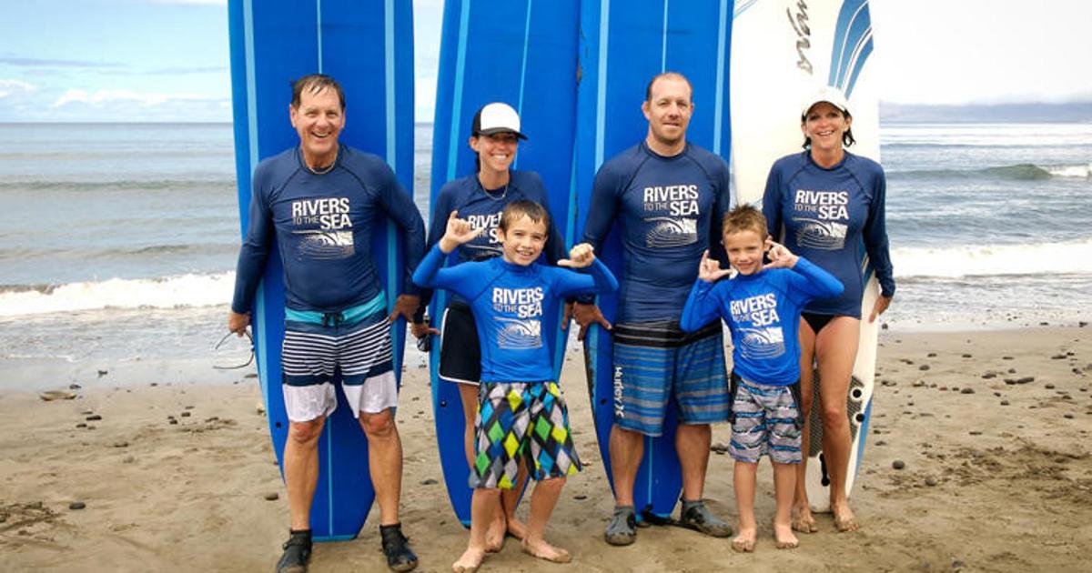 a group of people standing in front of a surfboard