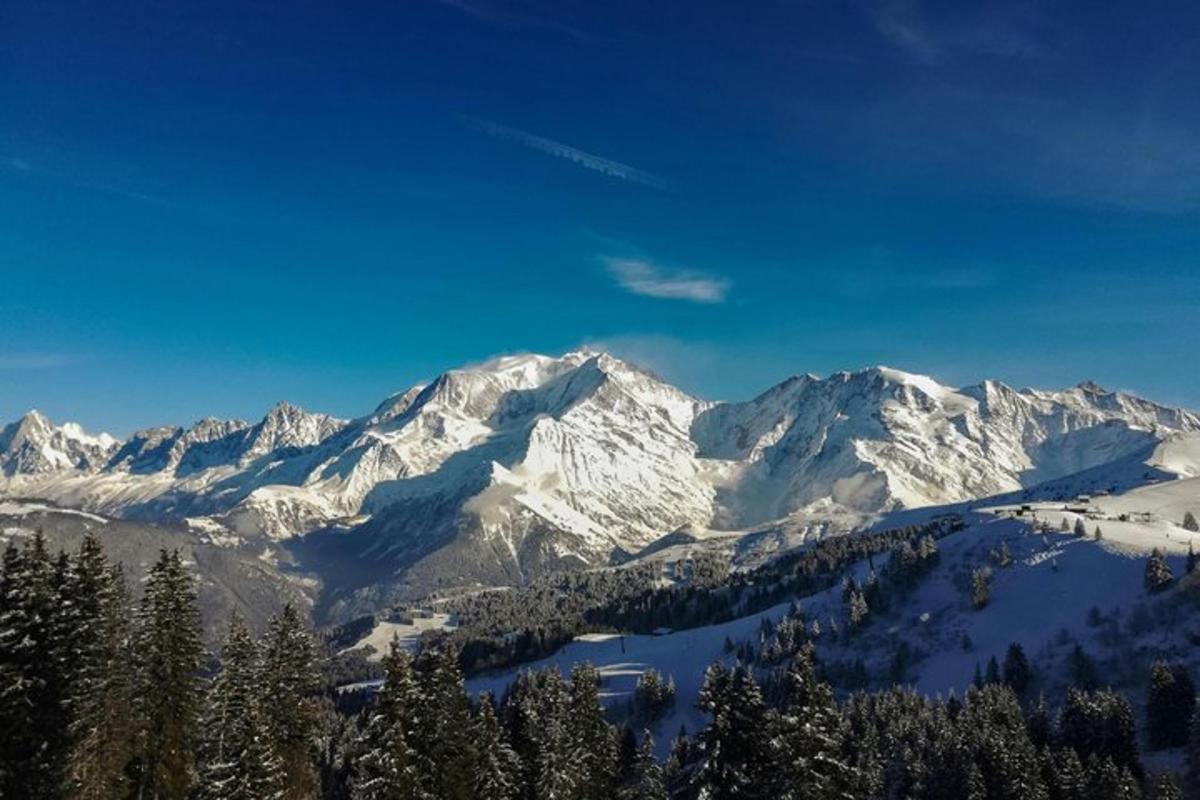 a snow covered mountain range with a lake in the foreground