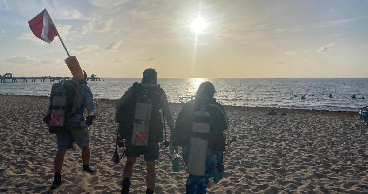 a group of three people walking on the beach