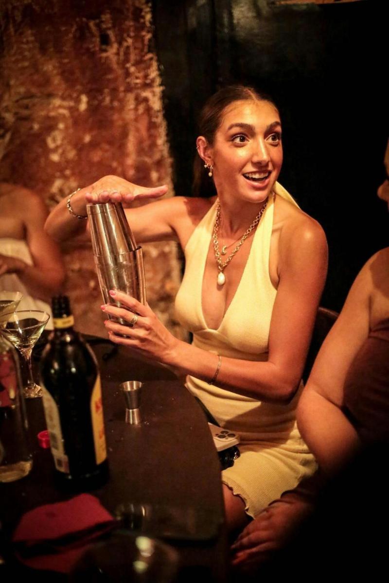 a woman sitting next to a table with a glass