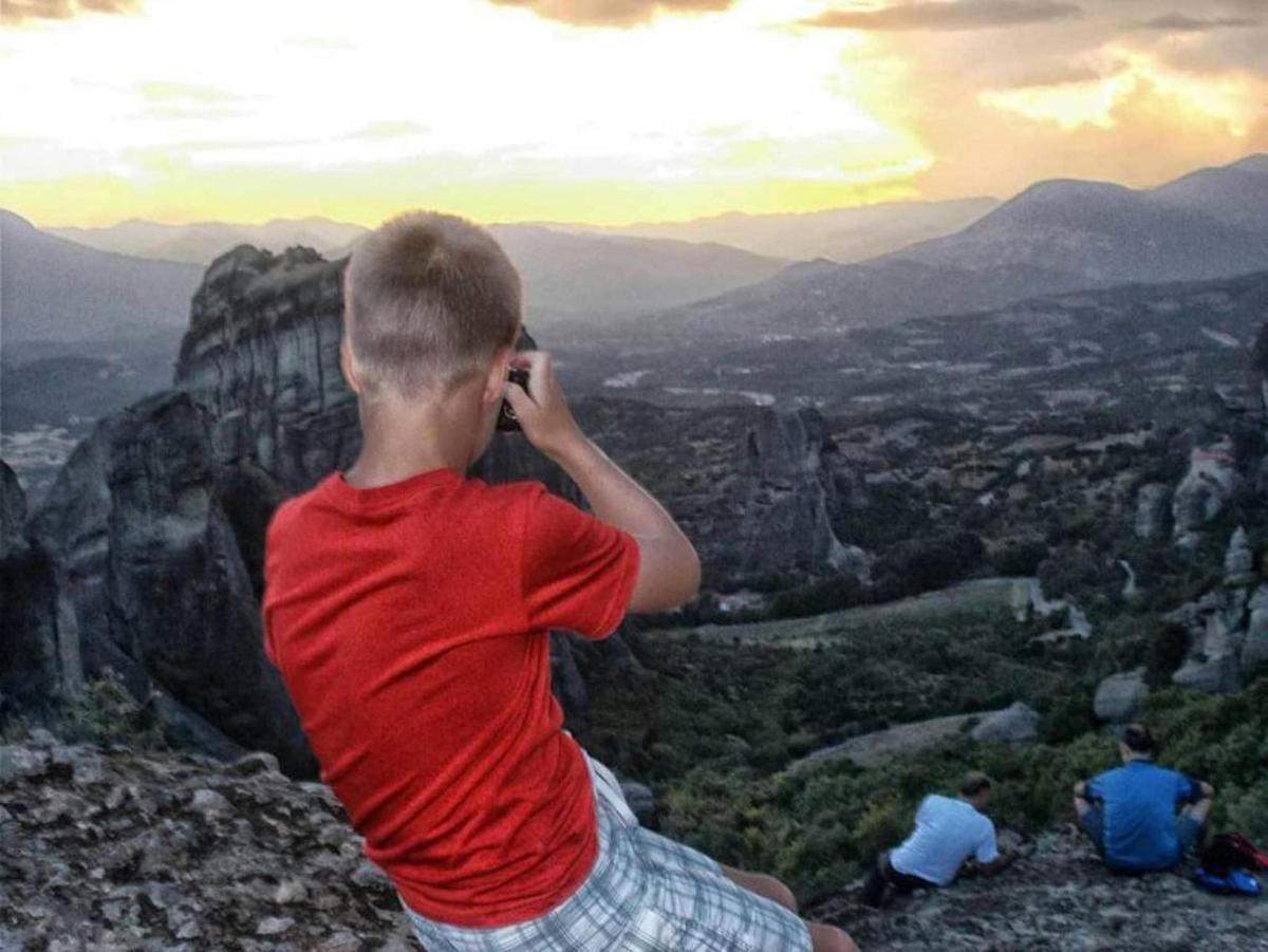 a boy talking on a cell phone on top of a mountain