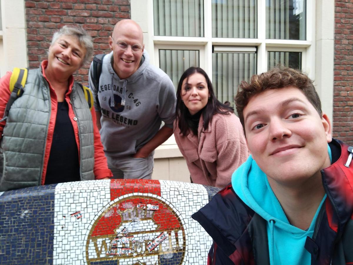 a group of people standing around a mosaic table