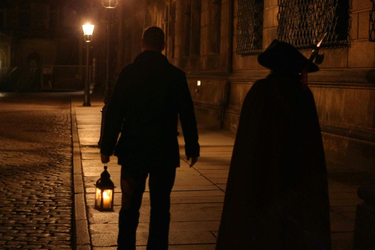 a man and a woman walking down a street at night