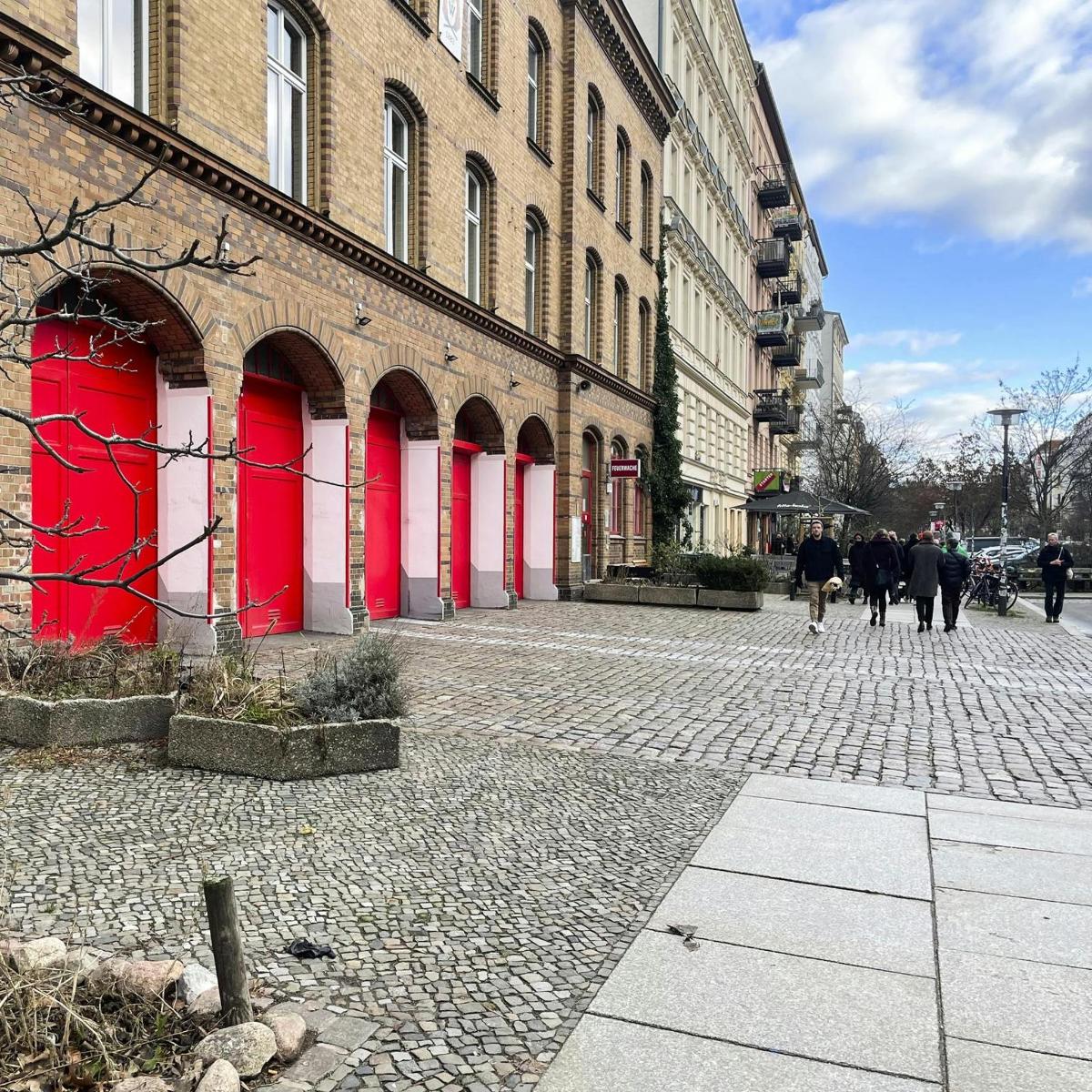 a brick street with red doors on a building