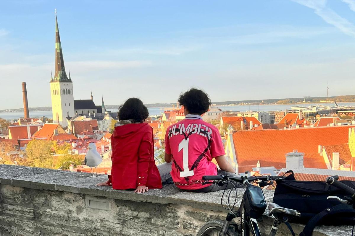 two people sitting on a wall looking at a city