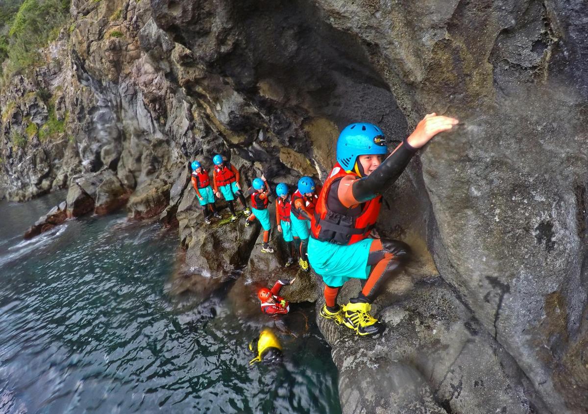 a group of people rappelling down a rock cliff