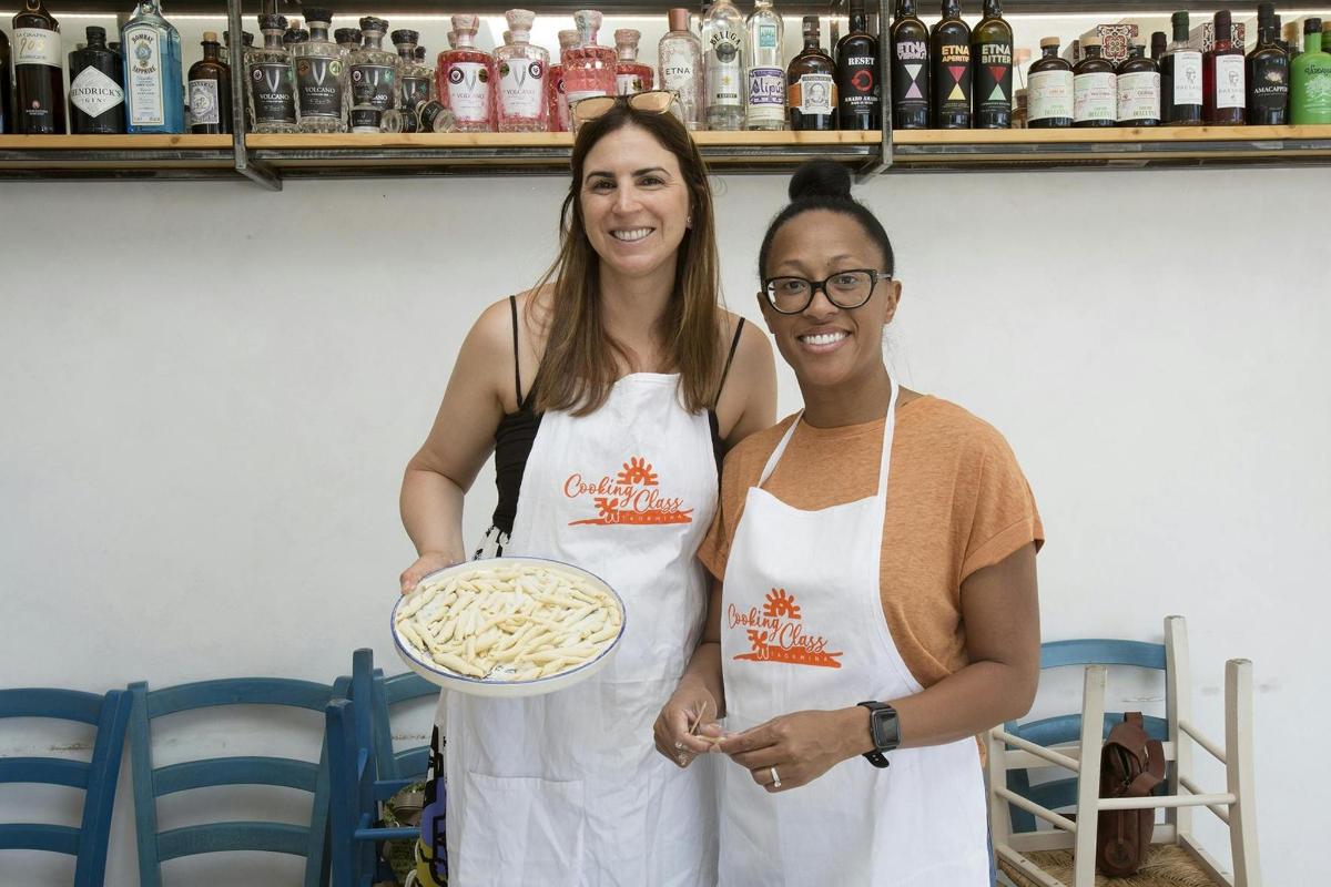 two women standing next to each other holding a plate of food