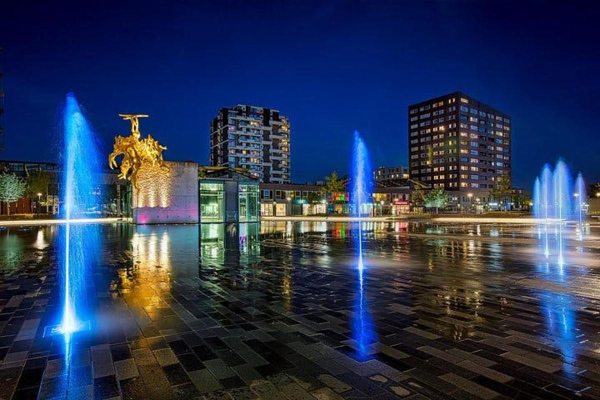 a city with fountains in a square at night