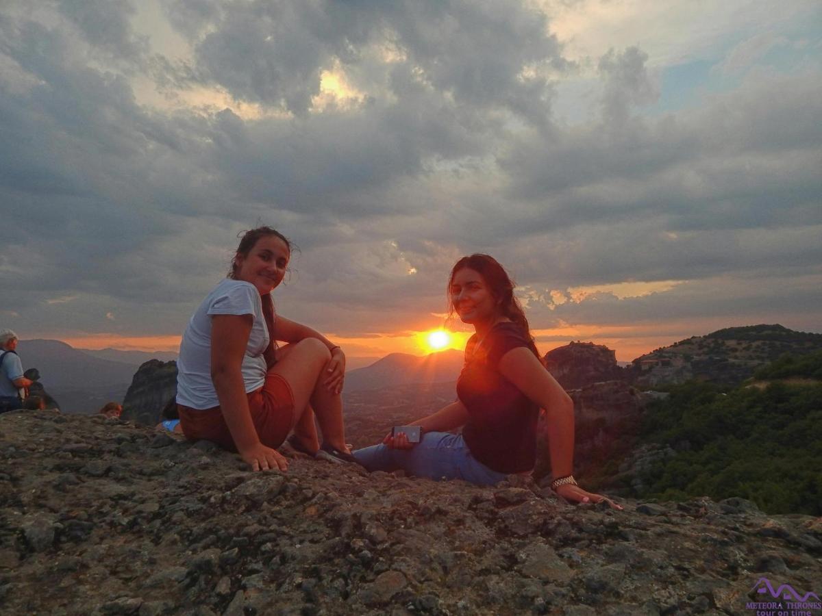 two women sitting on top of a mountain watching the sunset