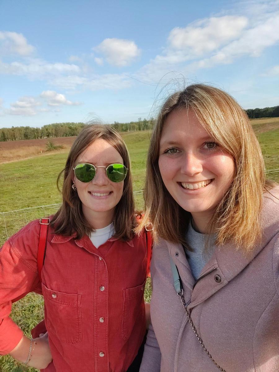 two women standing next to each other in a field