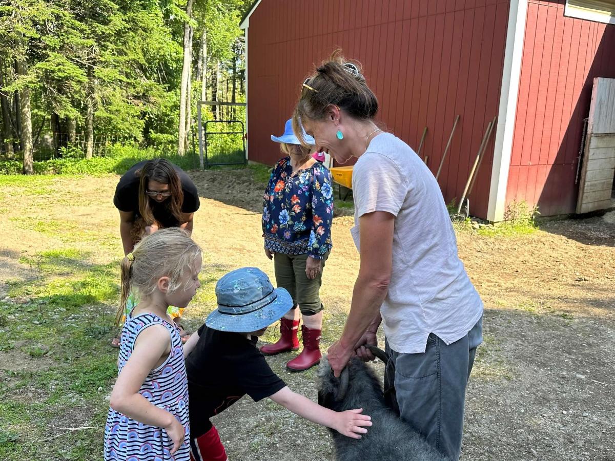 a group of children and a woman petting a goat