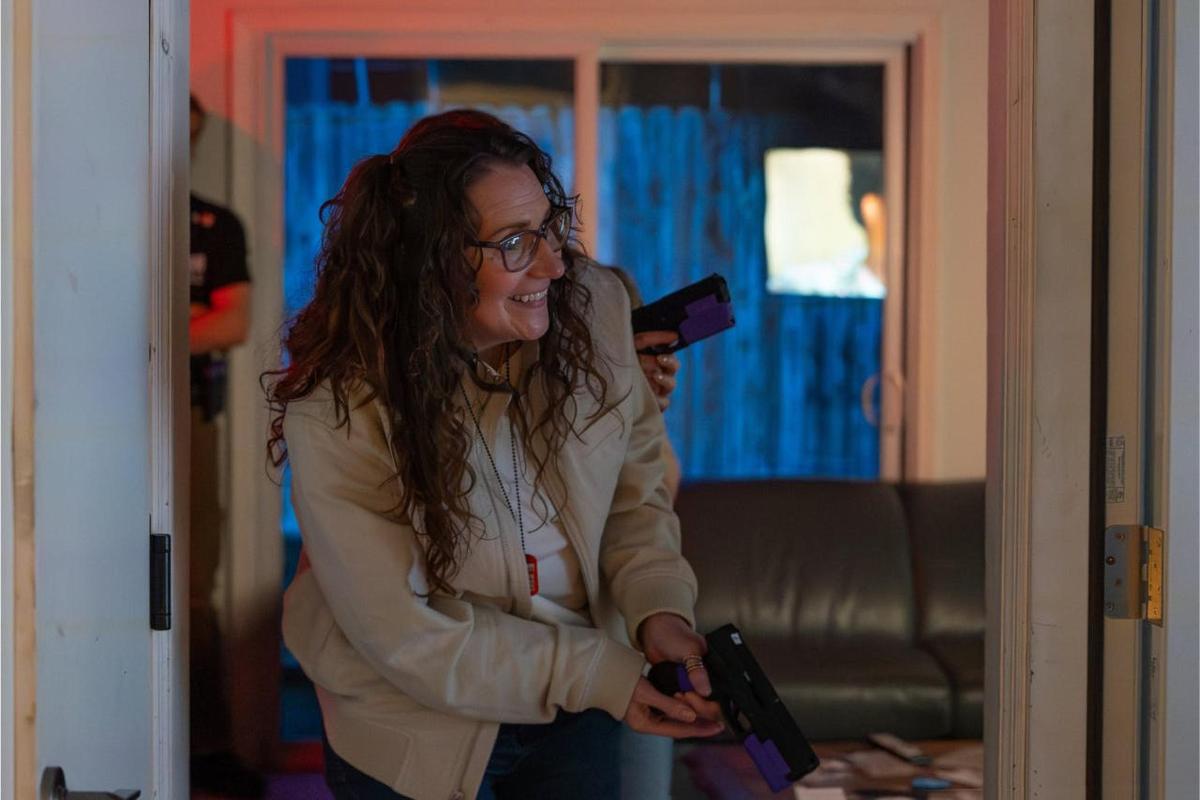 Uma mulher está rindo enquanto segura um secador de cabelo.